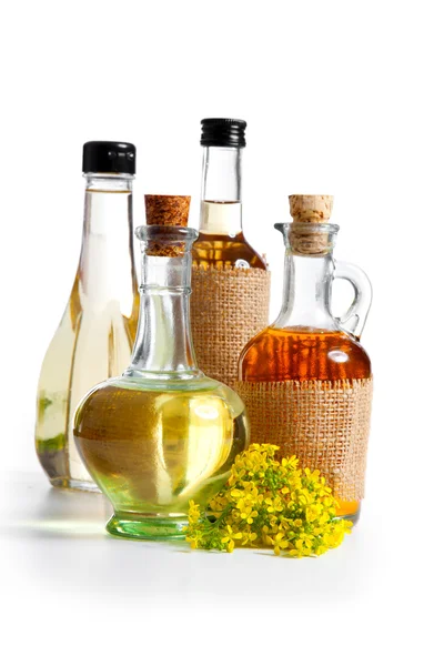 Bottiglie di olio vegetale e di oliva con fiori di colza, isolate su fondo bianco — Foto Stock