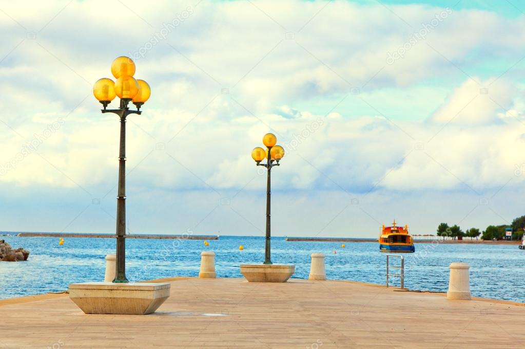 wooden berth with street-lamp on sea background. Pula Croatia