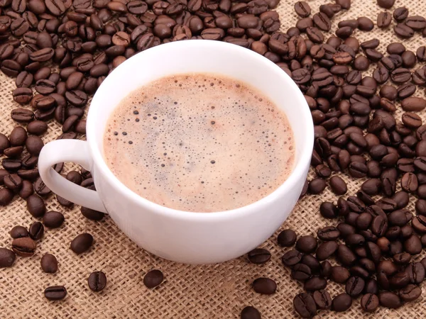 Koffie bonen met cup op doek — Stockfoto