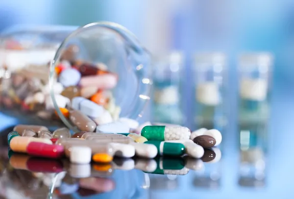 Красочные таблетки с капсулами и таблетками на синем фоне Стоковое Фото