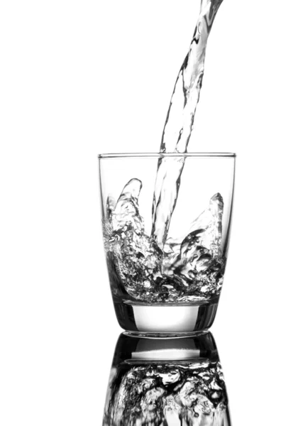 Wlewając wodę w szklance na białym tle — Zdjęcie stockowe