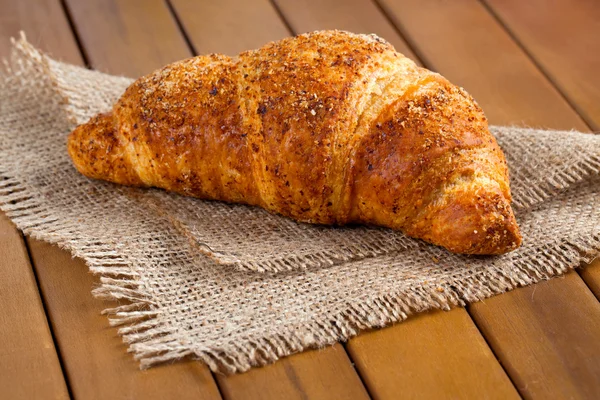 Croissant fresco e saboroso no fundo de madeira — Fotografia de Stock