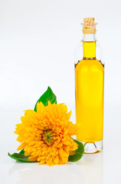 Olie in glazen fles en zonnebloemen, geïsoleerd op wit — Stockfoto