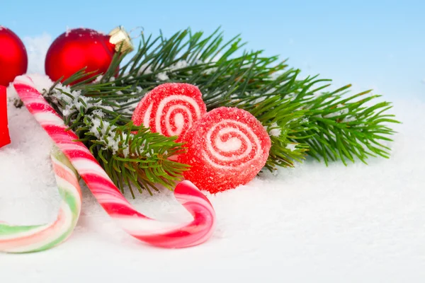 Decoração de Natal com bastões de doces, em um fundo de neve falso — Fotografia de Stock