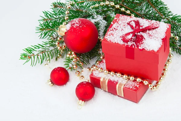 Rode kerstcadeau met feestelijke decoraties op sneeuw achtergrond — Stockfoto