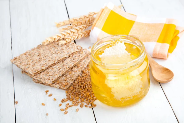Med s dřevěnou lžící a křupavý chléb na dřevěné pozadí — Stock fotografie