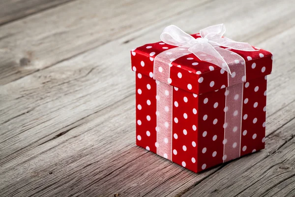 Caja de regalo roja con lazo sobre fondo de madera — Foto de Stock