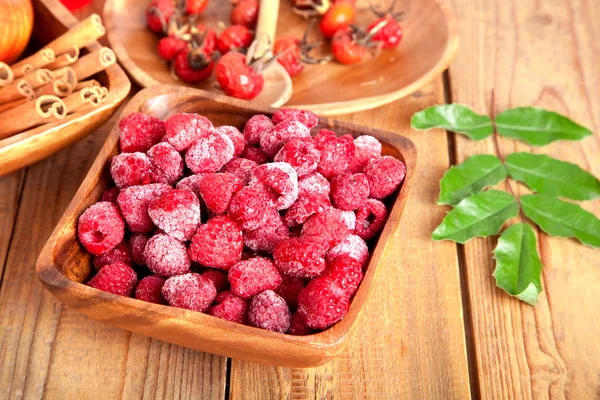 Frozen raspberries in the wooden bowl with spoon — Stock Photo, Image