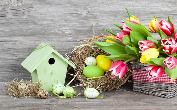 Decoración de Pascua con huevos, pajareras y tulipanes. backgr de madera —  Fotos de Stock
