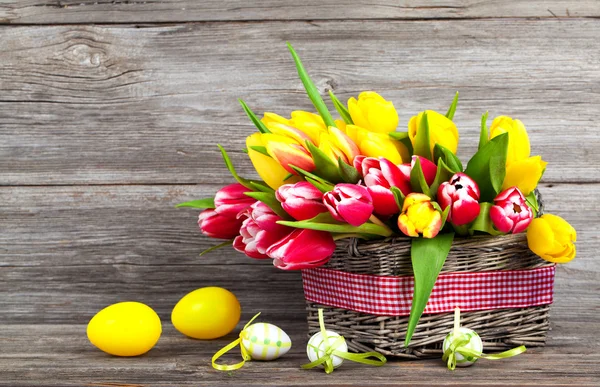 Tulipas primavera em cesta de madeira com ovos de Páscoa, em backg de madeira — Fotografia de Stock