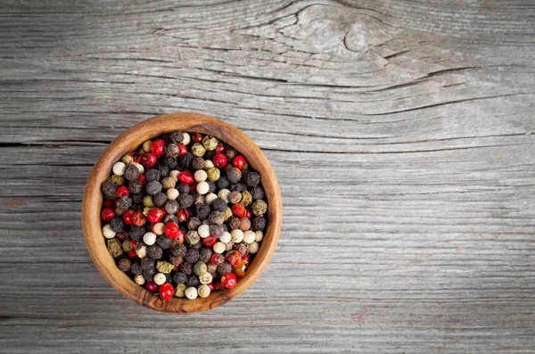 Colored Pepper in the wooden bowl, on wooden board — Stock Photo, Image