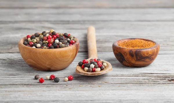 Colored Pepper in the wooden bowl, on wooden board — Stock Photo, Image