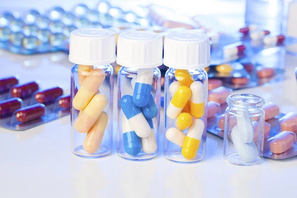 Capsule mediche colorate in bottiglia, su sfondo bianco . — Foto Stock