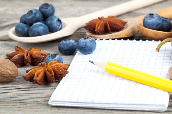 Anteckningsbok och penna med ingredienser mat på träbord — Stockfoto