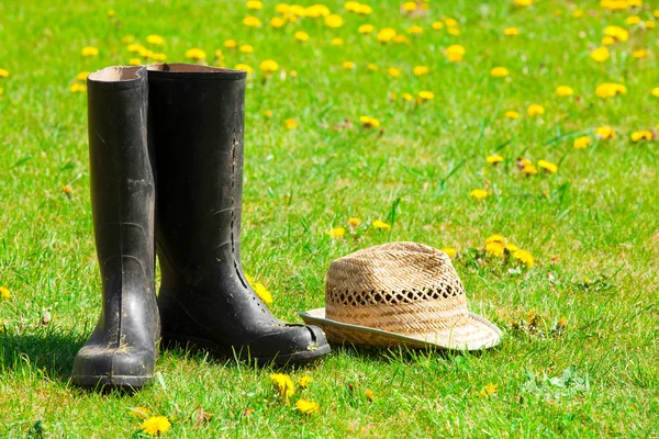 Garden boots and straw hat on the grass in the garden — Stock Photo, Image