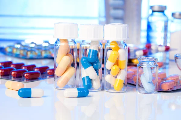 Capsule mediche colorate in bottiglia, su sfondo bianco . — Foto Stock