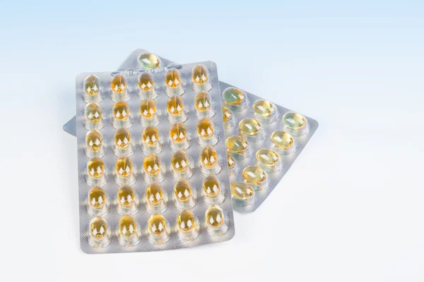 Vissen olie capsules en blister pack geïsoleerd op blauwe achtergrond. — Stockfoto