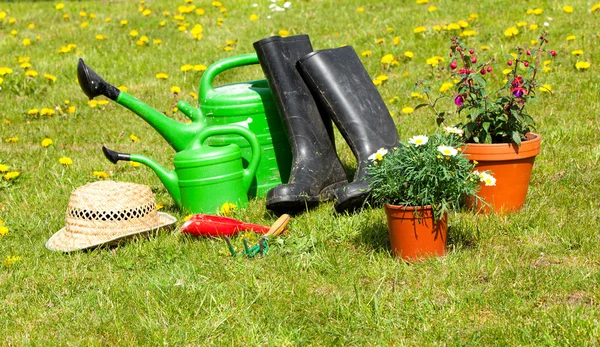 Gardening tools and a straw hat on the grass in the garden — Stock Photo, Image