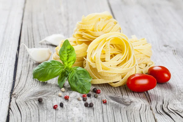 Nido de fettuccine de pasta italiana con ajo, tomates y ba fresca —  Fotos de Stock