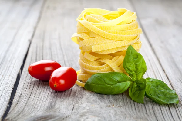 Nido de fettuccine de pasta italiana con tomates y pulga de albahaca fresca —  Fotos de Stock