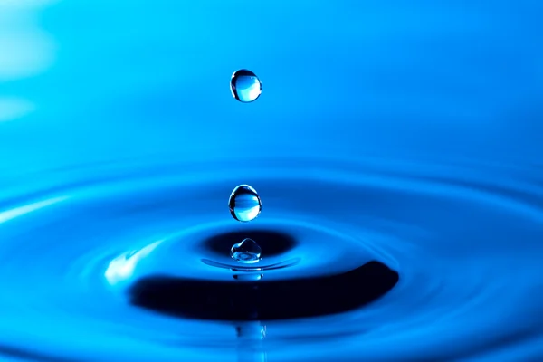 Stříkající vodě koruny na modrém povrchu — Stock fotografie