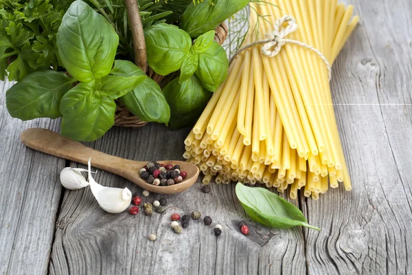Espaguetis con ajo, pimientos y hojas de albahaca fresca en madera — Foto de Stock