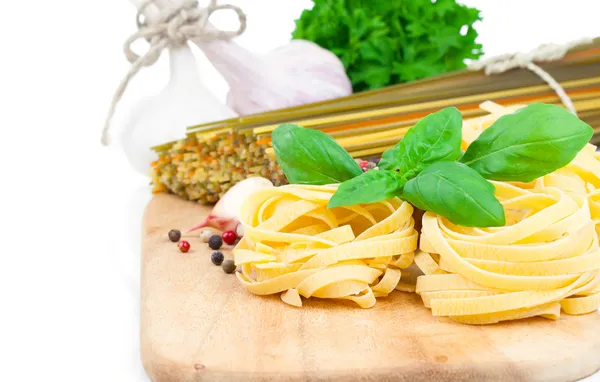 Ninho de macarrão italiano fettuccine com folhas de manjericão fresco, em branco — Fotografia de Stock