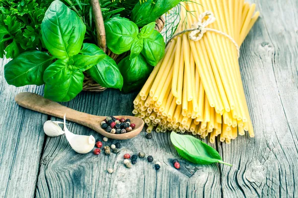 Spaghetti with garlic, peppers, and fresh basil leaves on wooden — Stock Photo, Image