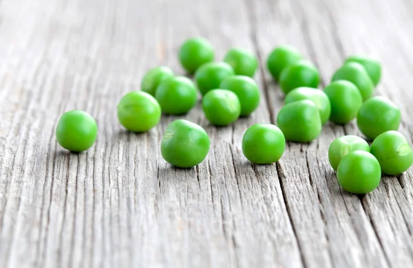 Ervilhas verdes em fundo de madeira — Fotografia de Stock