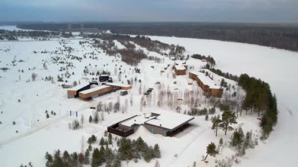 宾馆的小建筑 座落在美丽的地方 坐落在雪白冰封的冬江岸边的松树丛中 鸟瞰着整个冬季 — 图库视频影像