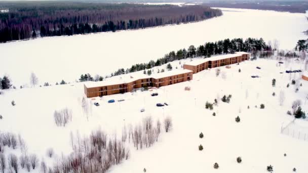 小さなホテルの建物は 美しい場所に位置し 冬の川のほとりの松の木の中に雪に覆われた白い氷で覆われ 鳥の目のビューから 動画クリップ