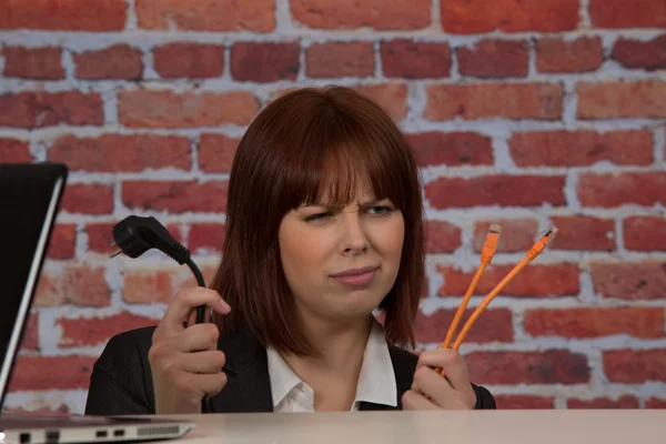 Confused woman plugging in her laptop — Stock Photo, Image