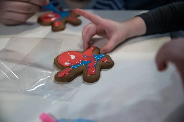 Çocuklar zencefilli ekmeği örümcek adam şeklinde boyarlar. Yüksek kalite fotoğraf