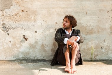 bir duvarın önünde oturan çocuk