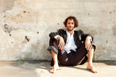 bir duvarın önünde oturan çocuk