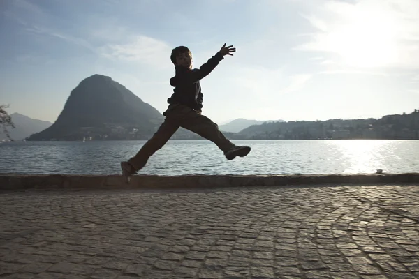 Прыжок ребенка возле озера — стоковое фото