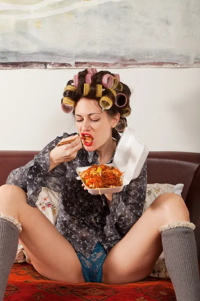 Sexy girl eating spaghetti on the couch — Stock Photo, Image