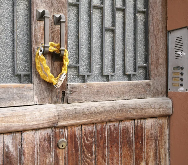 Serratura chiusa con catena gialla su una vecchia porta in legno — Foto Stock