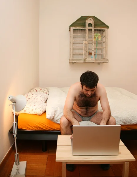 Άνθρωπος πληκτρολογώντας, κάθεται στο κρεβάτι — Φωτογραφία Αρχείου