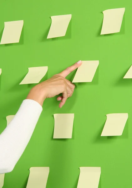 Рука на зеленой стене с бумажными записками — стоковое фото