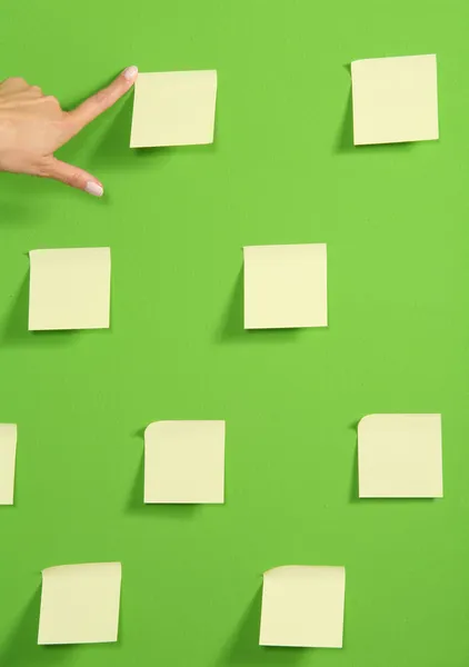 Hand auf grüne Wand mit Zetteln — Stockfoto