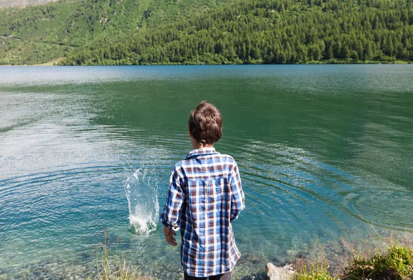 Boy on the shore of a mountain lake — Stock Photo, Image