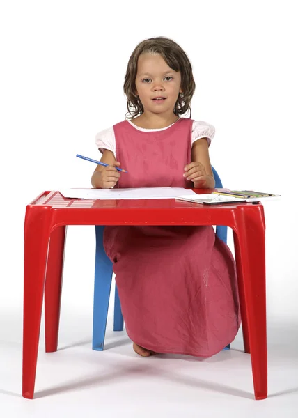 Holčička u stolu kreslí pastelkami — Stock fotografie