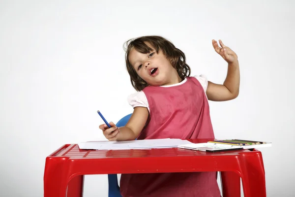 Klein meisje aan de tafel trekt — Stockfoto