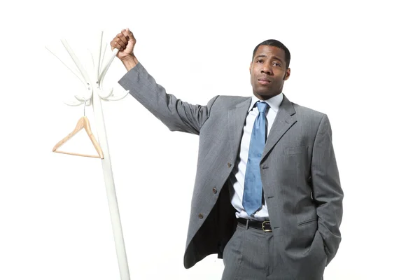 Black businessman leaning coat rack — Stock Photo, Image