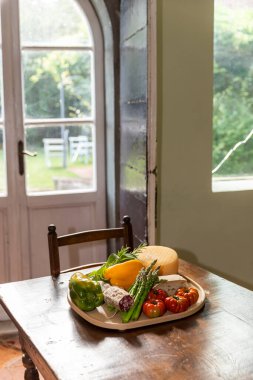 Büyük, yuvarlak bir tepsi Akdeniz yemeği. Arkasında büyük tahta bir kapı var.