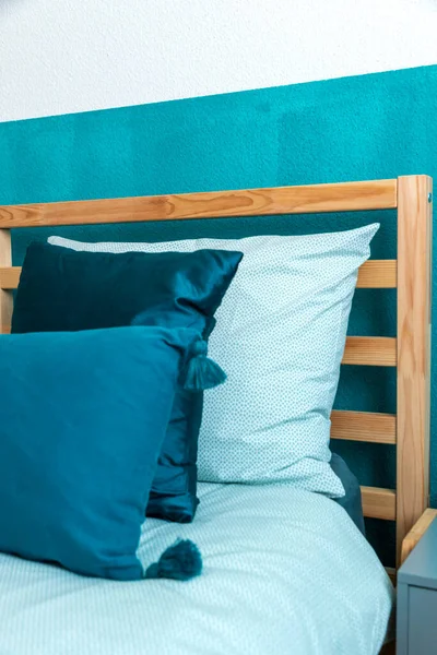 板の上にターコイズ色の壁と多くの枕を持つ木製のベッドの詳細 親密さと静けさの感じ 誰も中に — ストック写真