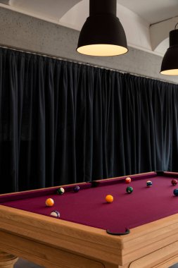 Sahneyi aydınlatmak için topları ve büyük lambaları olan bir bilardo masasının ayrıntıları. Arka planda siyah perdeler var. İçeride kimse yok.