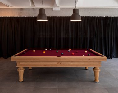 Sahneyi aydınlatmak için topları ve büyük lambaları olan bir bilardo masasının ayrıntıları. Arka planda siyah perdeler var. İçeride kimse yok.