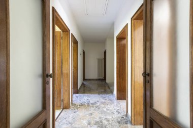 Ahşap kapıları ve mermer zemini olan koridor. İçeride kimse yok.